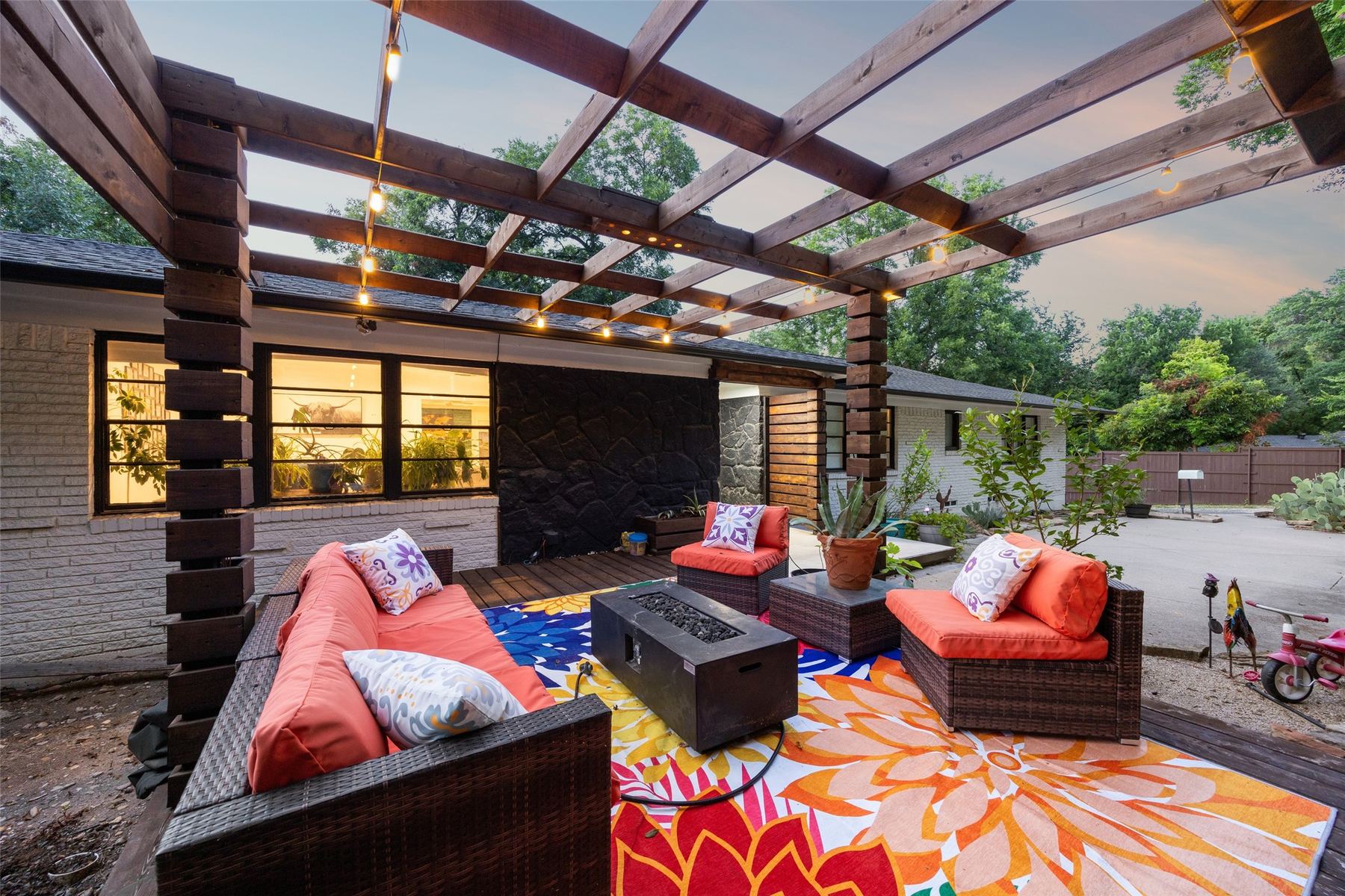 Covered pergola patio at 1657 Nob Hill Rd at dusk, with outdoor sofas, a fire pit table and string lights above.